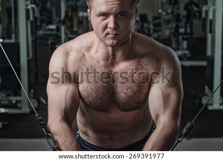 Young man at the gym exercise on the pectoral muscles, the reduction in the hands of crossover.Toning, hard light.