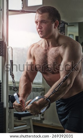 Young man at the gym exercise on the pectoral muscles, the reduction in the hands of crossover.Toning, hard light.