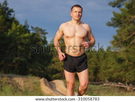 Young muscular man jogging outdoors on a summer evening.