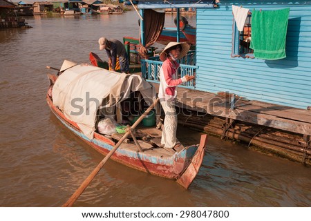 A woman with a big paddle in the boat with a makeshift cabin 02 December 2009, the boat was at the house, the host ties the boat to the dock of his home, a floating village of Tonle Sap Lake, Cambodia