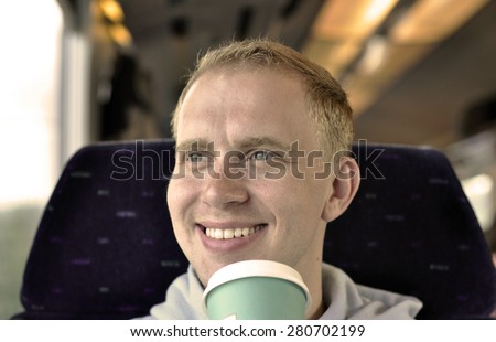 A young guy traveling by the train with cup of coffee - sepia effect