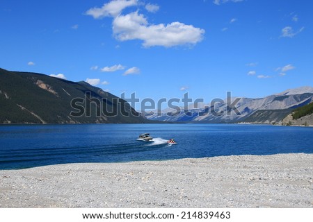 MUNCHO LAKE PROVINCIAL PARK, BRITISH COLUMBIA, CANADA - AUGUST 1, 2014: People boating in Muncho Lake Provincial Park, situated on the Alaska Highway between Fort Nelson, BC, and Watson Lake, YT.