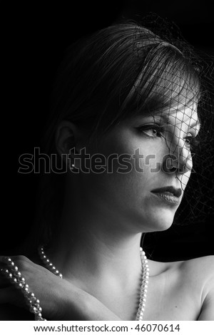 dramatic and low key black and white picture of a beautiful woman with a net veil