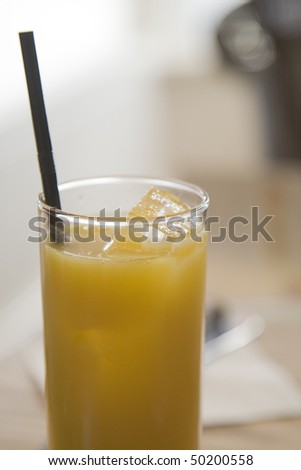 a glass of cold orange juice with ice and a straw