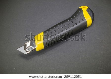 Utility knife with a retractable blade and yellow plastic handle with rubber insert