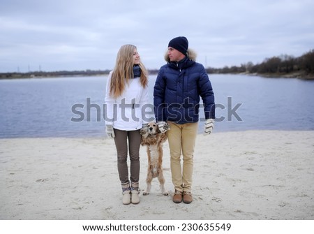 the guy, the girl and dog on a desert cold beach