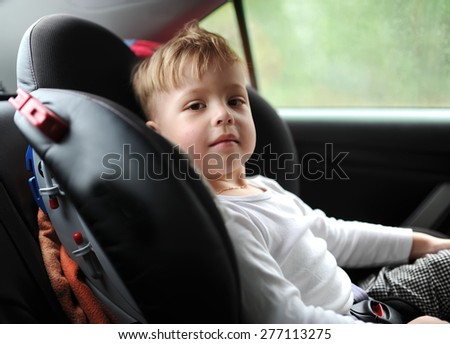 The kid sits in salon of the car on back sitting