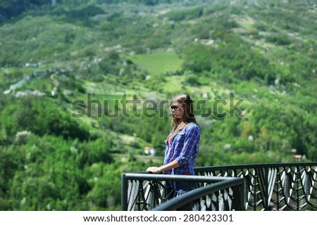the girl costs on a balcony of the ancient building and admires the nature