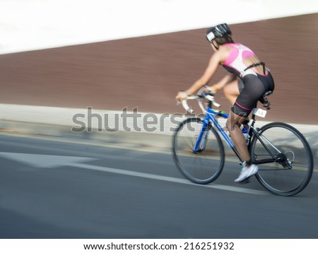 A cycling woman on a triathlon competition following an arrow, photo sweep