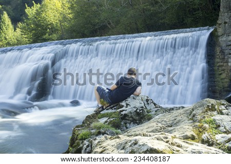 teenager in front of a dam, relaxing place to read a book