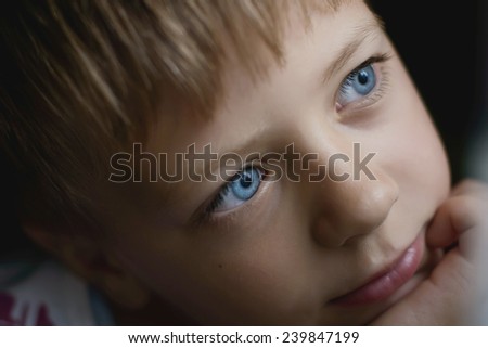 boy with blue eyes thinking while sitting by the window