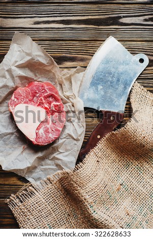 raw meat with the sacking on a wooden background with knife and ax