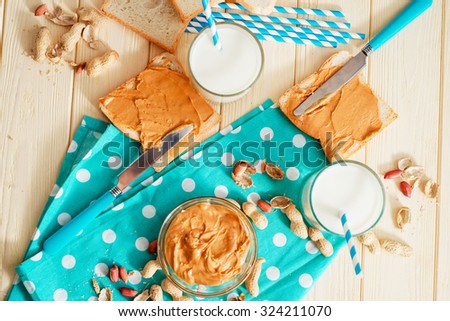 peanut butter sandwich with milk and peanuts on the wooden background