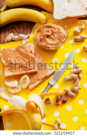 peanut butter sandwich with black tea, bananas and peanuts on the wooden background
