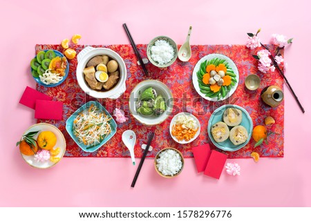Family dinning table of Tet holiday or Lunar New Year with traditional foods: pork belly and eggs braised in coconut water, pickles, rice, Banh Tet (rice cake), fried vegetables, bitter melon soup
