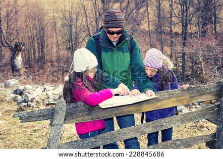 Family hiking in countryside looking for directions on the map.Cross processed.