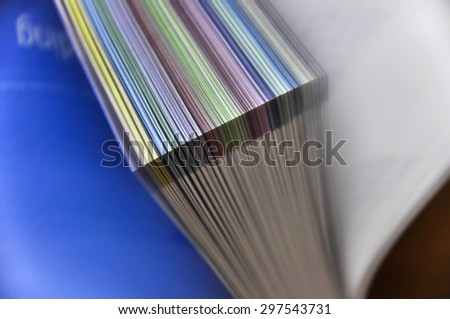 Detail of brochure pages with colored tabs being flipped through.