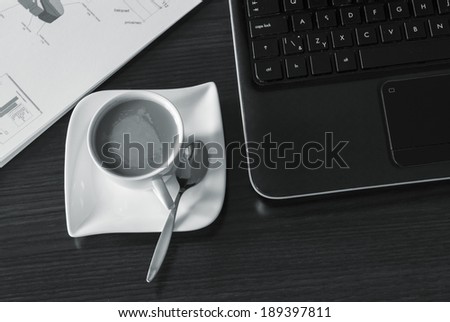 Open black laptop and hot cup of coffee on wood table