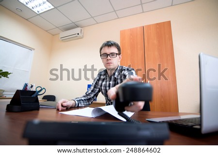 Office worker. Young office worker hangs up the phone