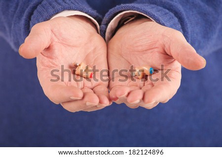 Old man\'s hands showing a pair of canal hearing aids (CIC)
