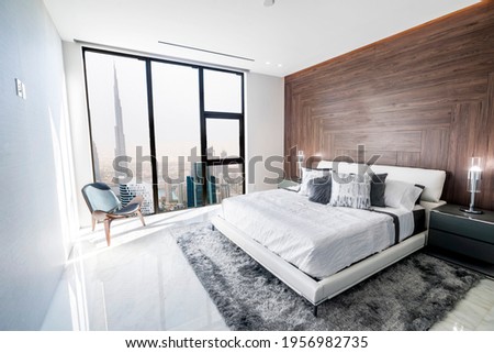 Modern and luxurious bedroom with white ceiling and wood accents with views of downtown Dubai skyline. Condo or Hotel accomodation.