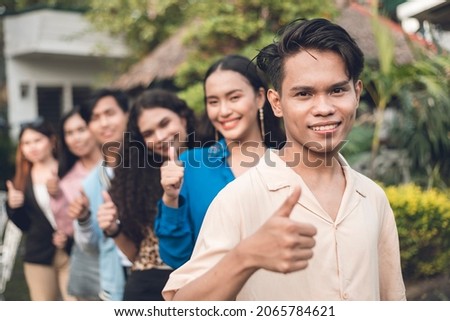 A group of six young and dynamic friends from late teens to early 20s, in a single file giving a thumbs up. Outdoor scene. Foto stock © 
