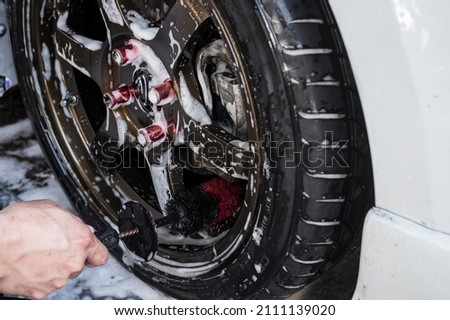 Using a wheel brush to scrub clean the interior spoke surface of a custom rim of a white sedan. At a carwash or auto detailing shop. Stock fotó © 
