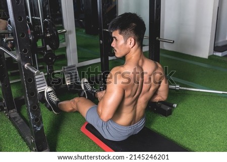 A shirtless asian man performing seated V-bar cable rows at the gym. Holding the rep for extra squeeze.Rowing machine exercise to train and develop back muscularity and mass. Stock fotó © 