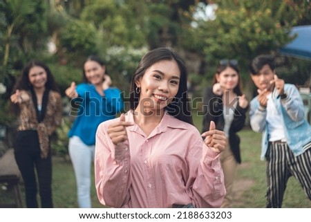 A cute and friendly woman makes heart finger signs together with her friends at the back. Five young asian people having fun. Friendship concept. Foto stock © 