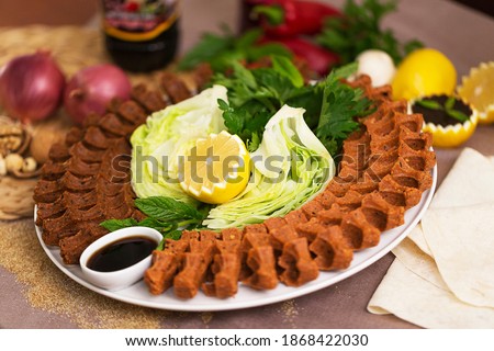 Cig kofte, a raw meat dish in Turkish and Armenian cuisines. Turkish cig means "raw" and kofte means meatball Turkish food raw cigkofte roll on wooden and black background Turkish food
