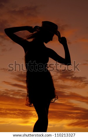 A silhouette of a woman in front of a sunset in her cowgirl hat.