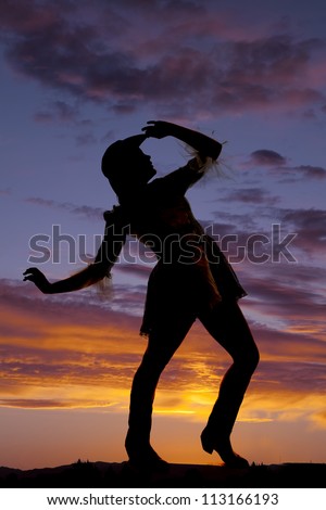 A silhouette of a woman dancing in the sunset.