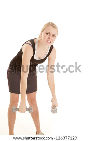 A woman leaning over with a tired expression and she can not lift her weights.