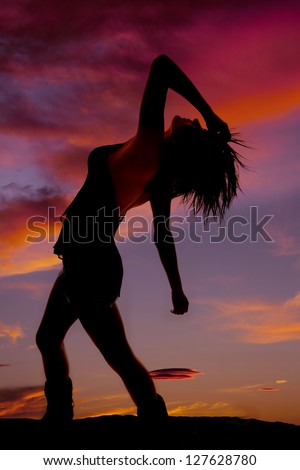 A silhouette of a woman leaning back in a sunset.