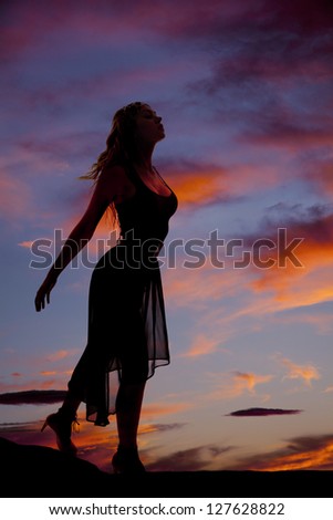 A silhouette of a woman with her arms reaching back.