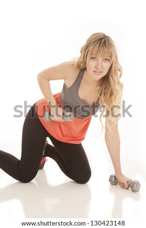 a woman with a smile working out her arms while on her knees.