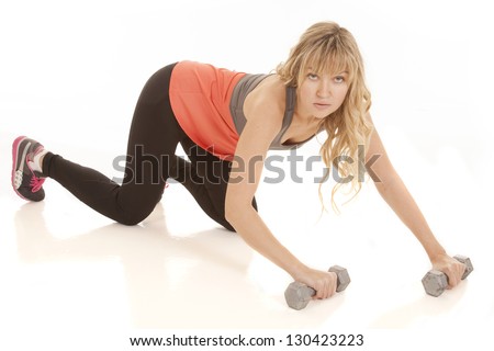 A woman on her knees holding on to weights with a serious expression on her face.