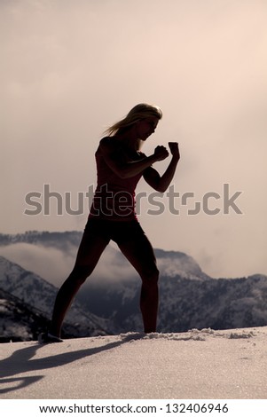 A silhouette of a woman working out boxing.