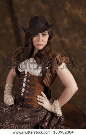 A woman in her vintage western dress and hat with a serious expression on her face.