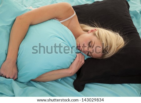 a woman laying on her pillow covered by another pillow asleep