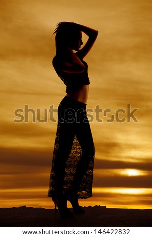 A silhouette of a woman in her lace skirt with her hands on her head