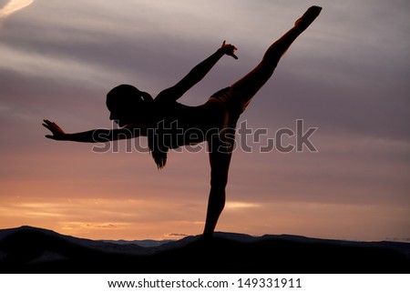 A silhouette of a woman doing a dance pose in the outdoors