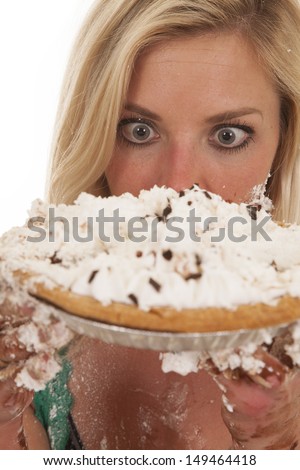 A woman has a pie by her face and is very messy.