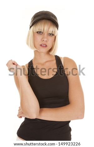 A woman in a black tank top and a hat looks serious.