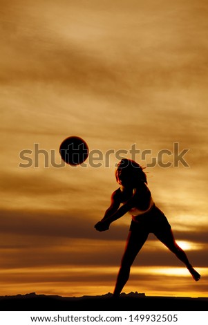 A silhouette woman playing volleyball with a beautiful sky.