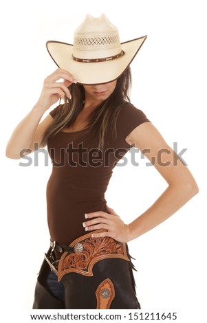A woman in her western wear in her chaps and hat looking down.