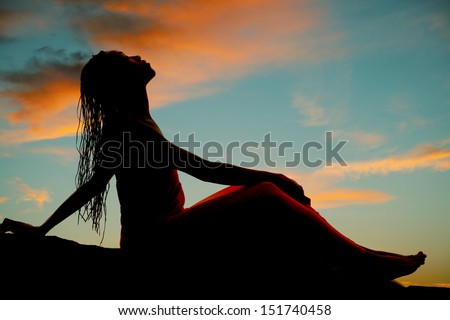 A silhouette of a woman leaning back with her braids falling back.