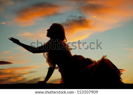 A silhouette of a woman laying down and reaching out to the side.