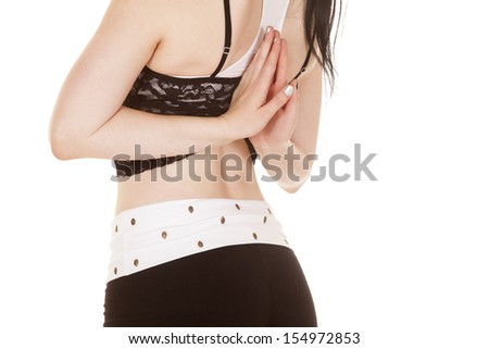 A woman in a lace top has her hands behind her back.