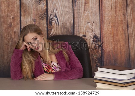 a woman working in her office looking at a pile of books not wanting to start working.